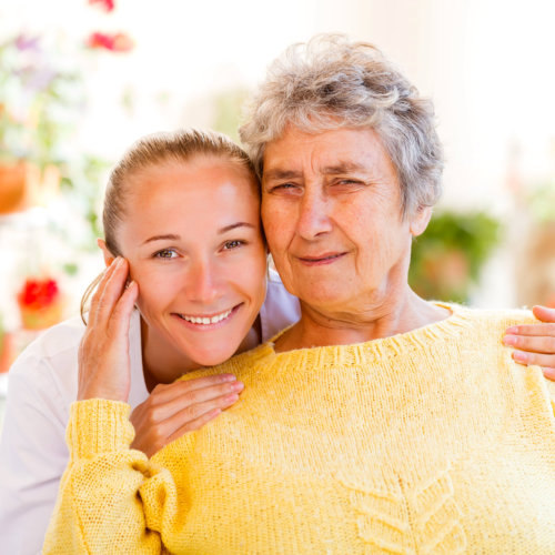 smiling old woman with her female caregiver at the garden