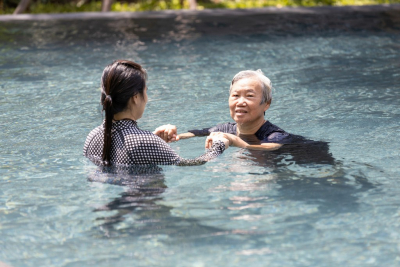 old woman doing swimming with her caregiver