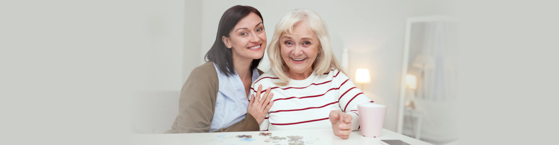 smiling female caregiver and her old woman patient