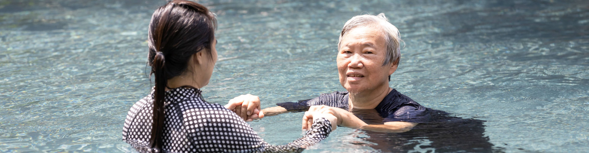 old woman doing swimming with her caregiver